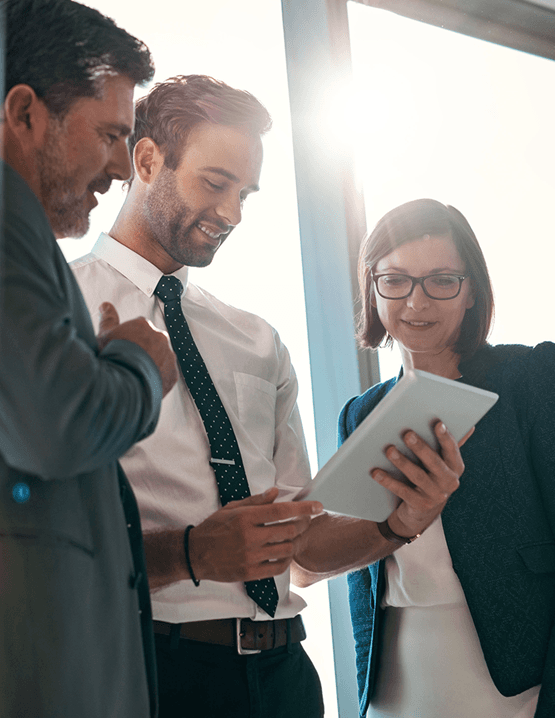 Three professionals collaborating and looking at a tablet in a meeting