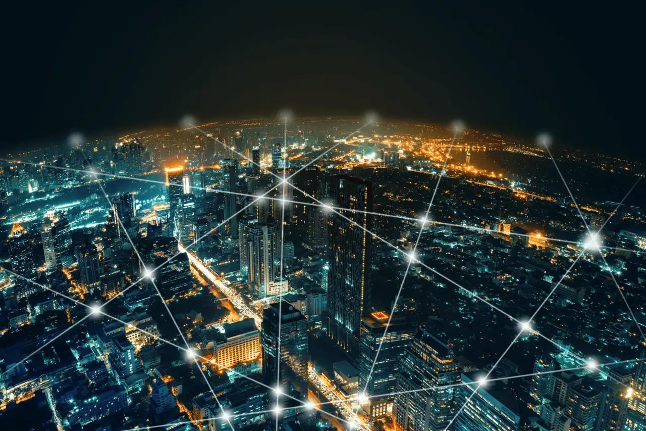 Spécialistes du support collaborant devant une visualisation de réseau numérique au-dessus d'une ville de nuit