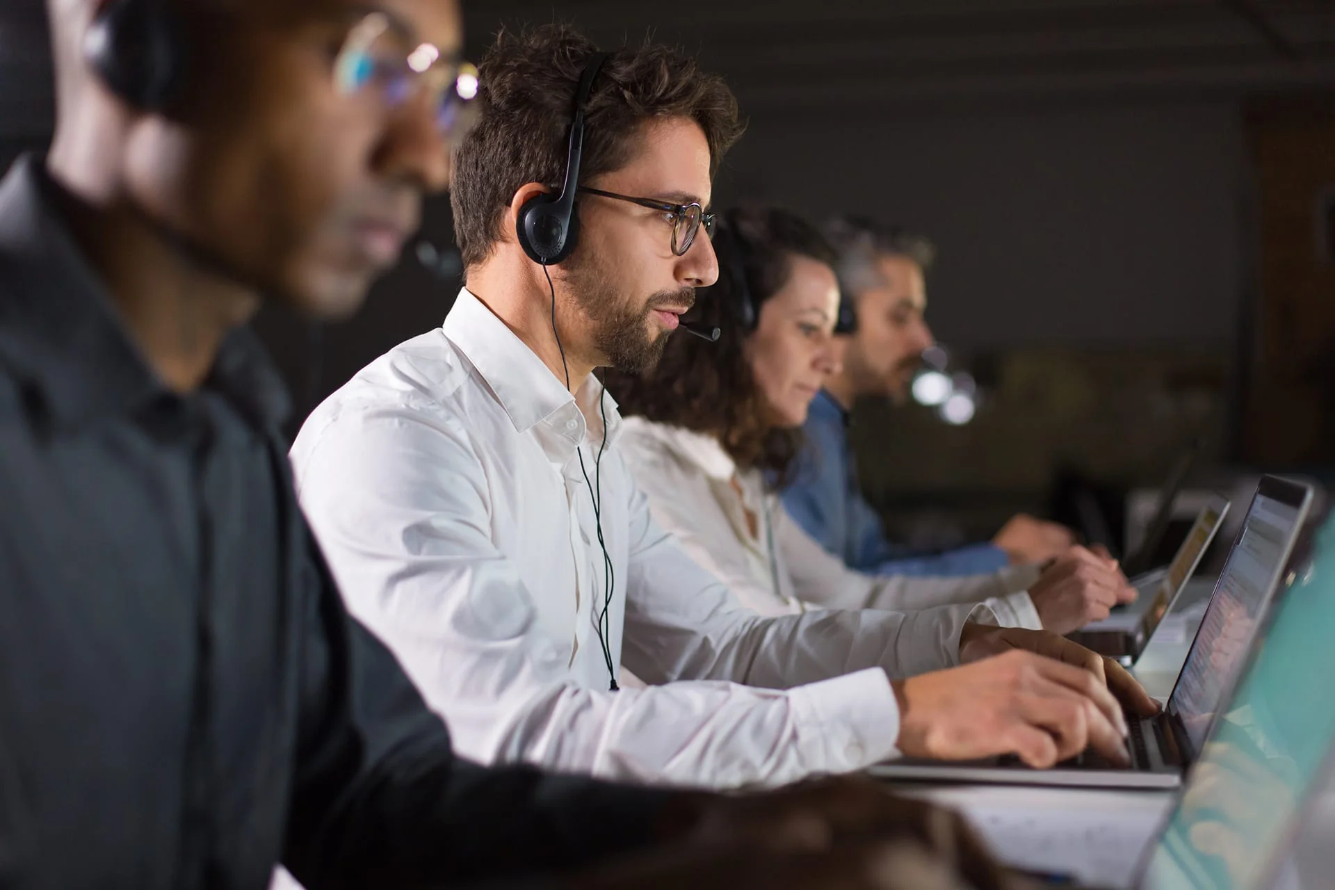 Specialista del supporto con cuffie al lavoro su un portatile